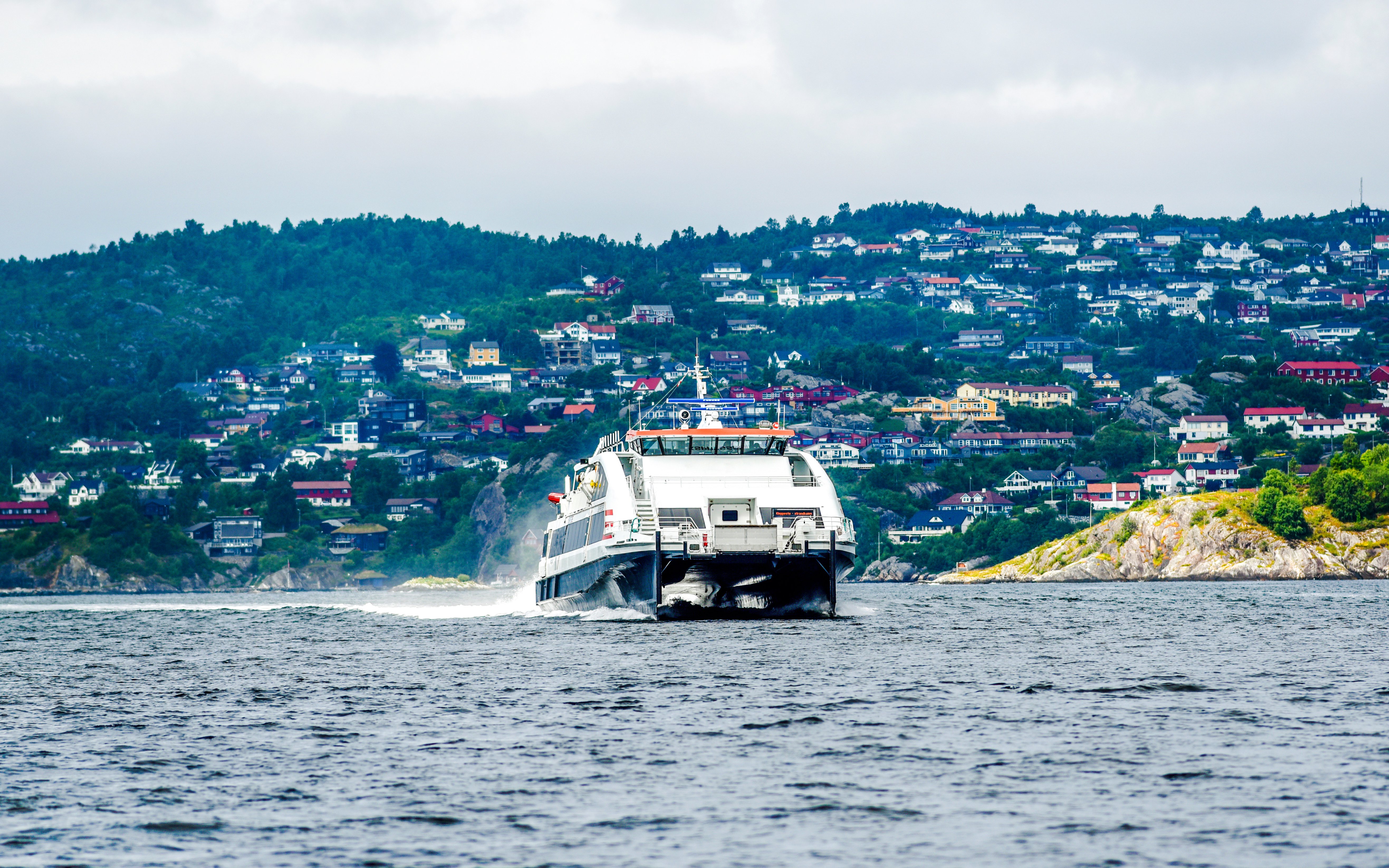 Ferry boat approaching Bergen, Norway with hillside houses in the background.