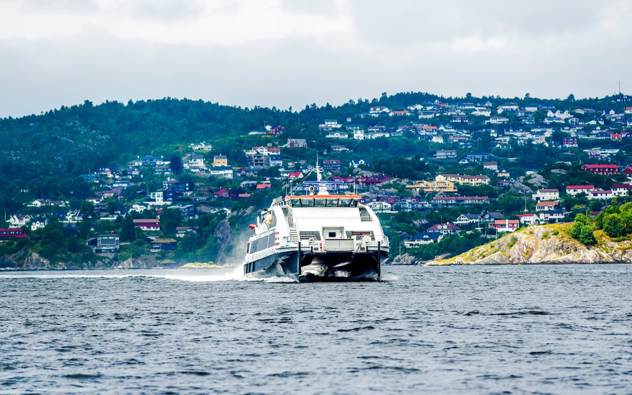 Ferry boat approaching Bergen, Norway with hillside houses in the background.