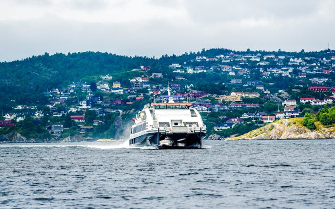 Ferry boat approaching Bergen, Norway with hillside houses in the background.