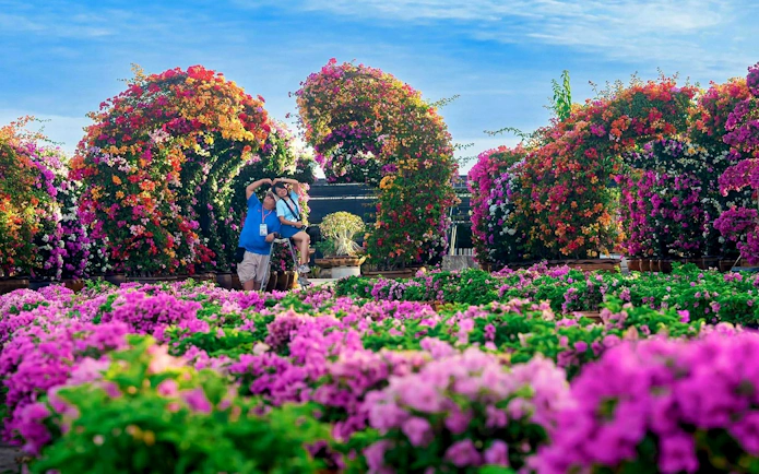 Visitors enjoying vibrant floral arches at Nong Nooch Tropical Garden.