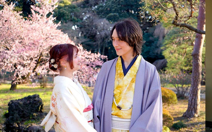 Couple in traditional kimonos at Shinjuku Gyoen National Garden, Tokyo, with cherry blossoms.