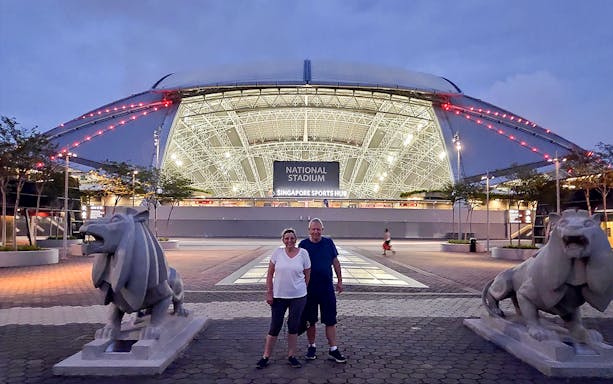 National Stadium at night with two people in front, part of Marina Bay bike tour.