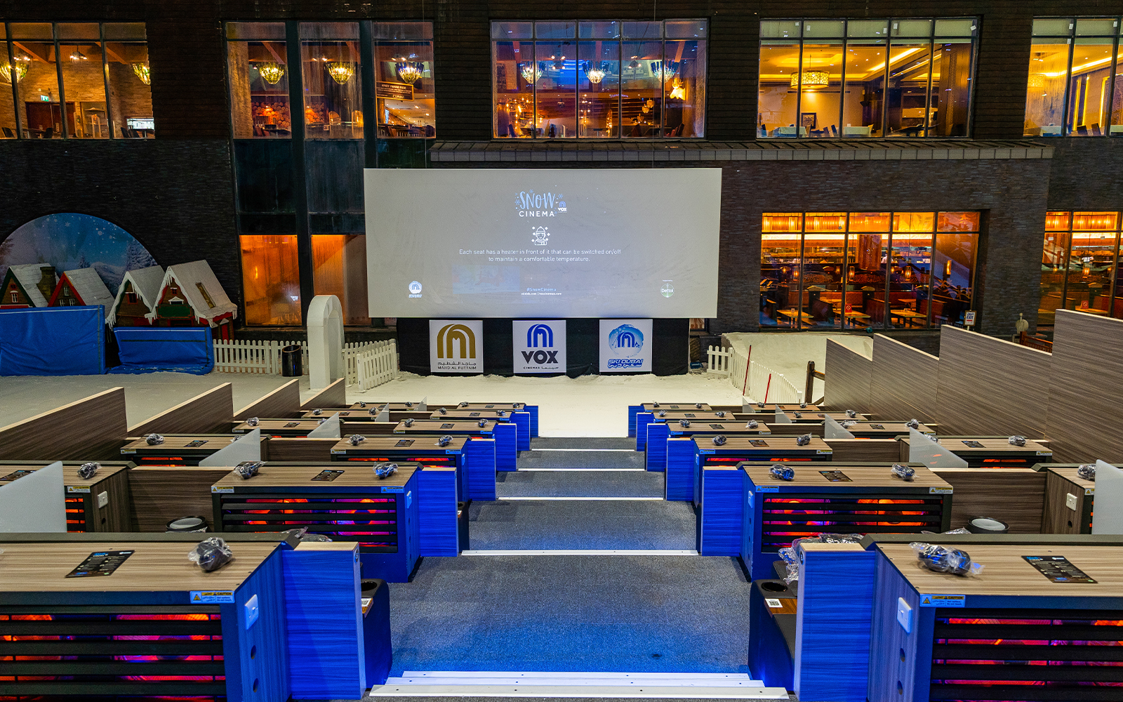 Seating area at Ski Dubai's Snow Cinema with a large screen and indoor snow setting.