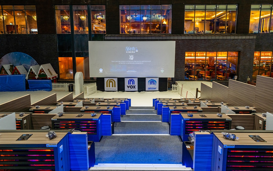 Seating area at Ski Dubai's Snow Cinema with a large screen and indoor snow setting.