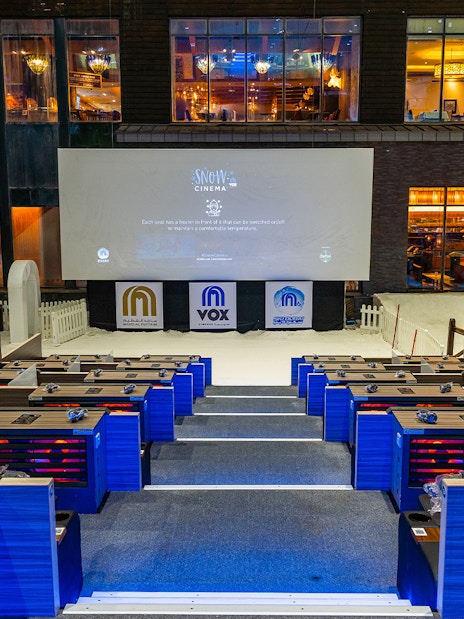 Seating area at Ski Dubai's Snow Cinema with a large screen and indoor snow setting.