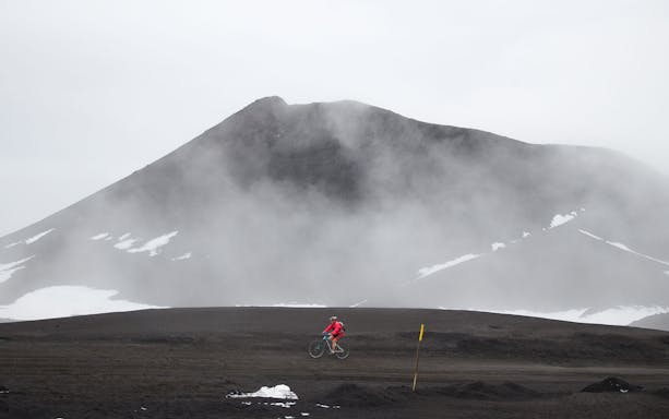 Cyclist on volcanic terrain near Mount Etna, Sicily, during e-bike tour.
