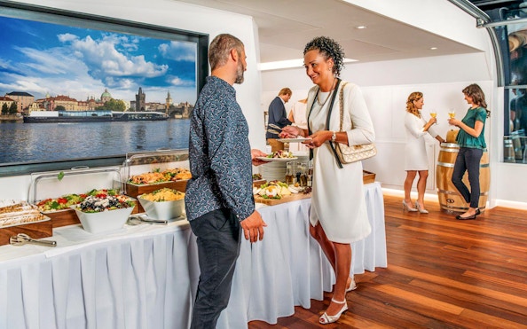 Guests enjoying a buffet on a Prague dinner cruise with a view of the Vltava River.