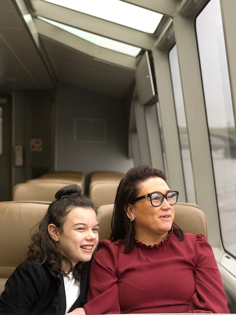 Passengers enjoying Thames River Uber Boat with London Eye view.