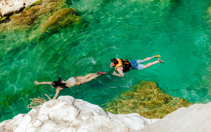Guests swimming in clear waters of Wadi Shab, Oman.