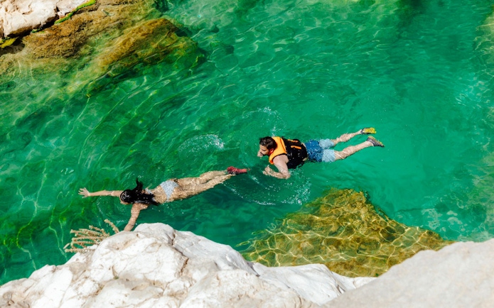 Guests swimming in clear waters of Wadi Shab, Oman.