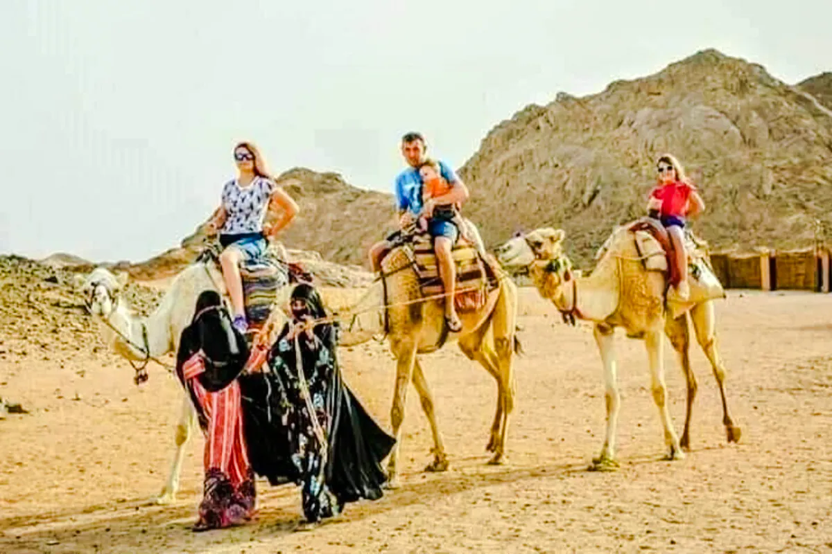 Tourists riding camels in the desert during a Hurghada safari trip.