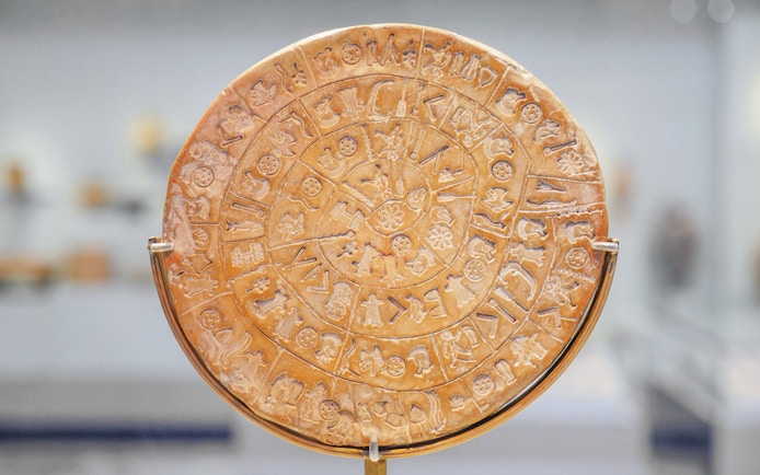 Phaistos Disk with ancient symbols in Archaeological Museum of Heraklion, Crete, Greece.