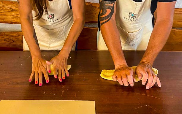 Hands kneading dough at Sardinian pasta workshop in Olbia.