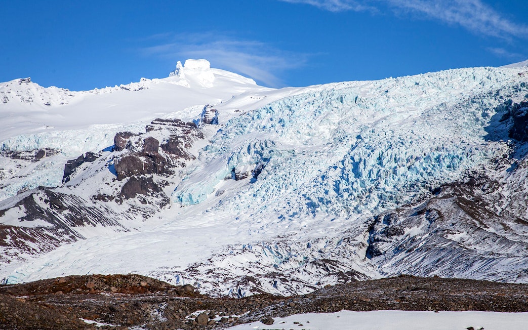 Falljökull glacier with icy blue crevasses and snow-covered peaks in Iceland.
