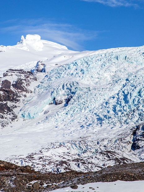 Falljökull glacier with icy blue crevasses and snow-covered peaks in Iceland.