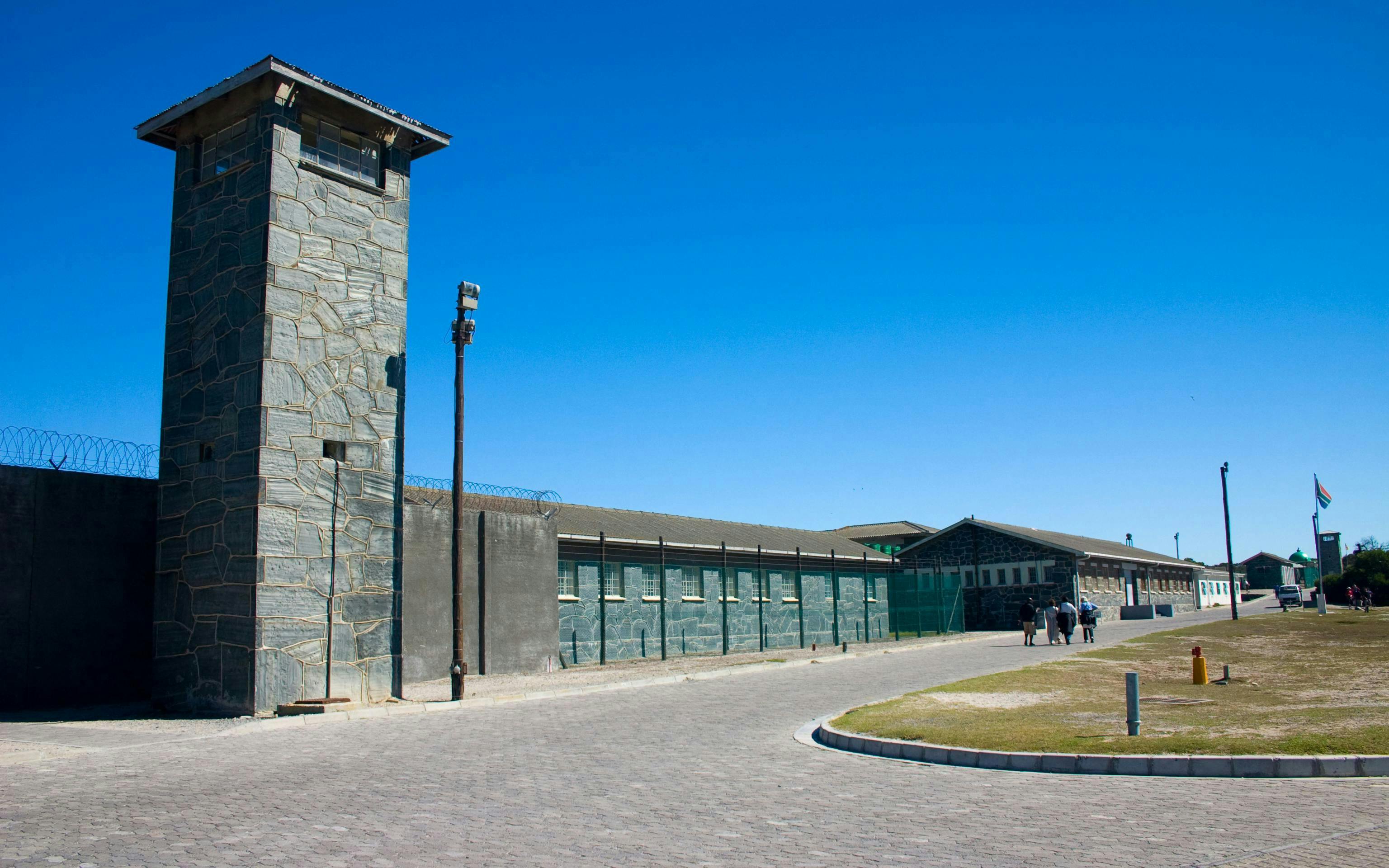 Robben Island Prison entrance with stone watchtower and barbed wire fence.