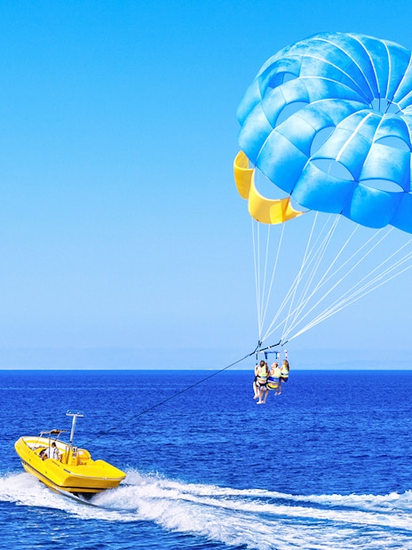 Parasailing over the ocean in Dubai with a yellow boat.