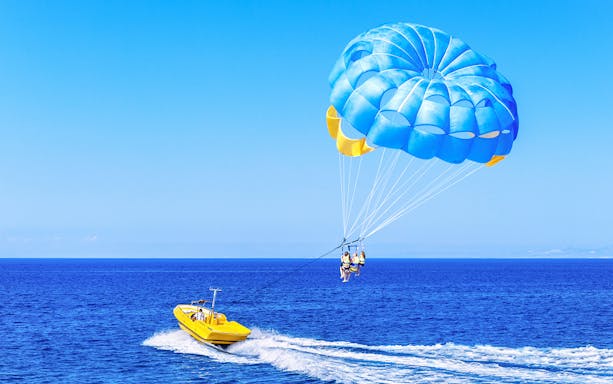 Parasailing over the ocean in Dubai with a yellow boat.