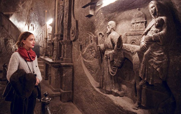 Visitor admiring intricate salt carvings at Wieliczka Salt Mine, Poland.