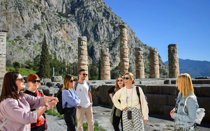Visitors exploring the Temple of Apollo ruins in Delphi, Greece.
