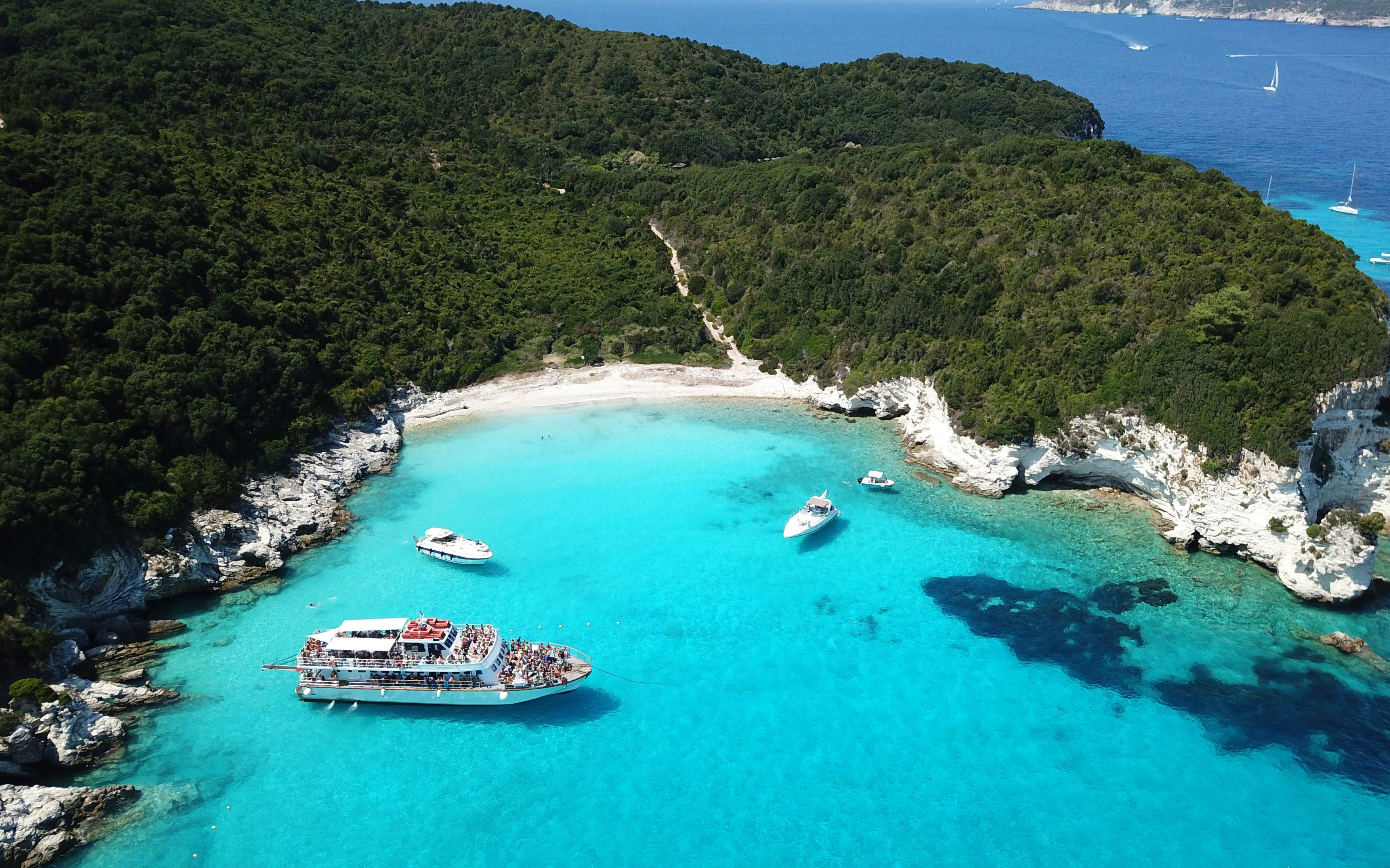 Aerial view of Voutoumi Beach with sailboats in turquoise waters, Anti Paxos, Greece.