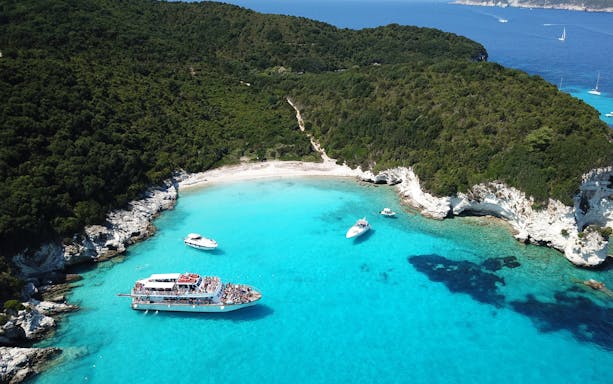 Aerial view of Voutoumi Beach with sailboats in turquoise waters, Anti Paxos, Greece.