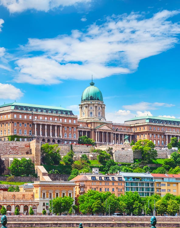 Buda Castle in Budapest with lush greenery and historic architecture.