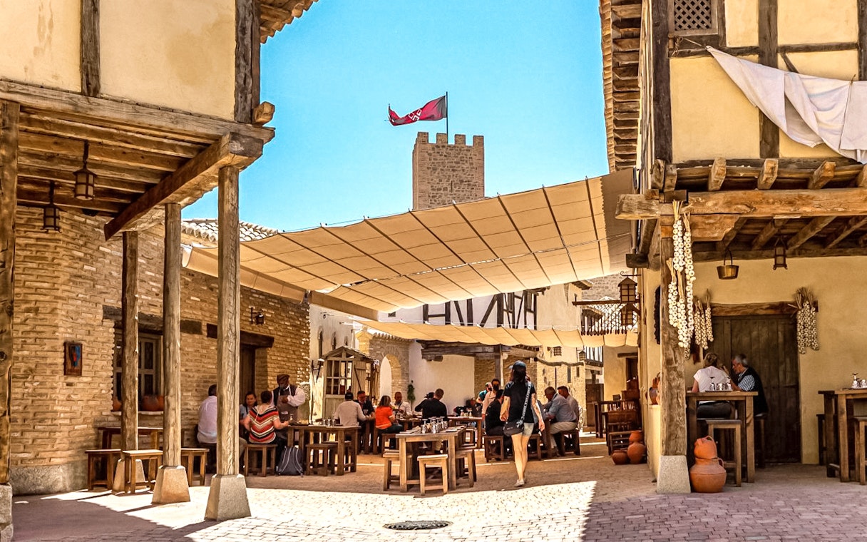 Visitors dining in a medieval village setting at Puy du Fou Park.