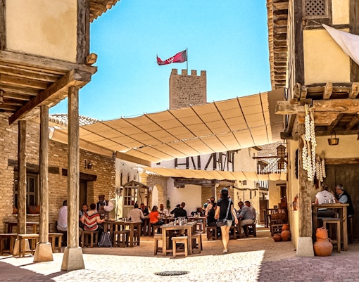 Puy du Fou Park medieval village scene with tourists enjoying food