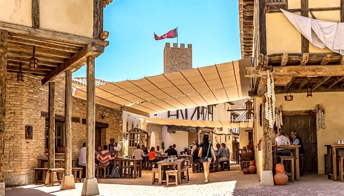 Puy du Fou Park medieval village scene with tourists enjoying food