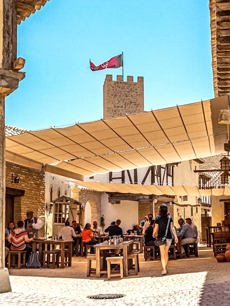 Visitors dining in a medieval village setting at Puy du Fou Park.