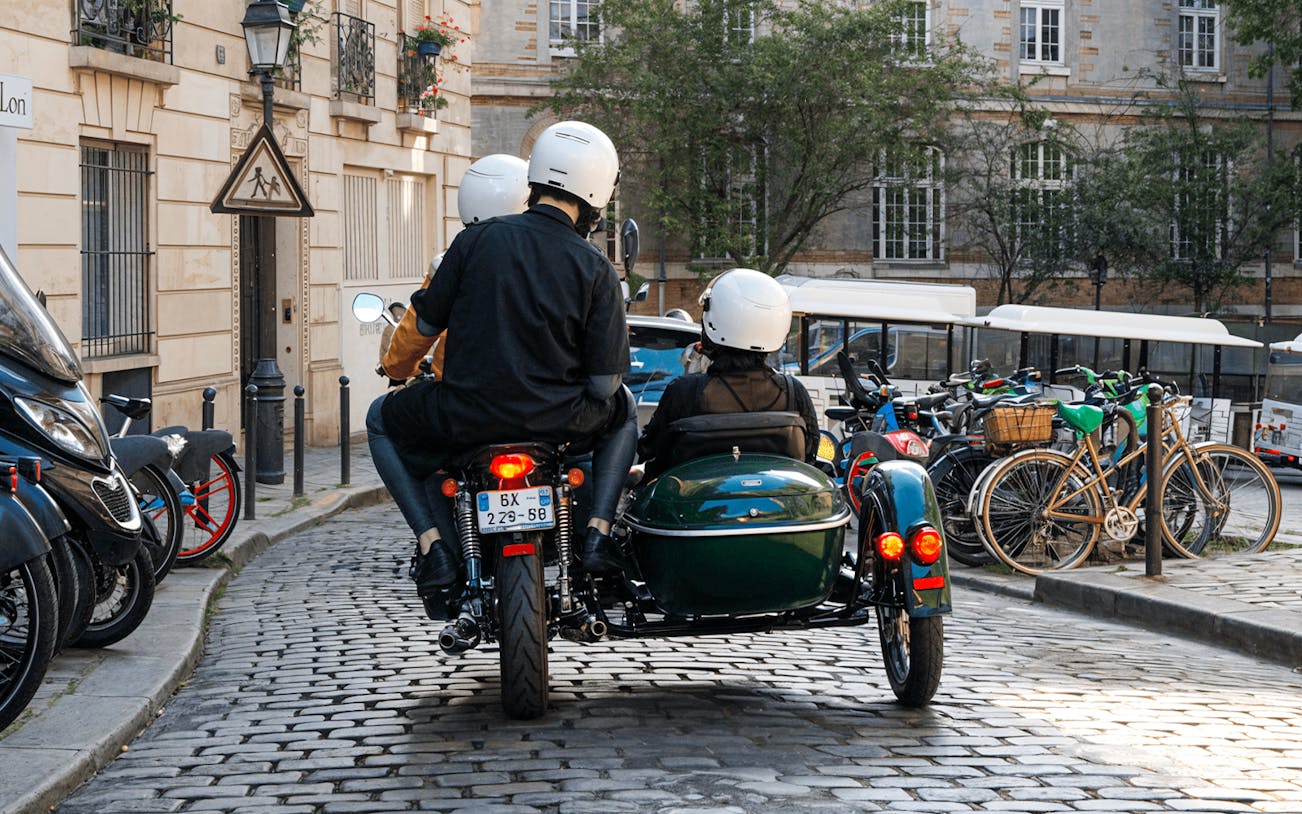Sidecar motorcycle tour on cobblestone street in Paris.