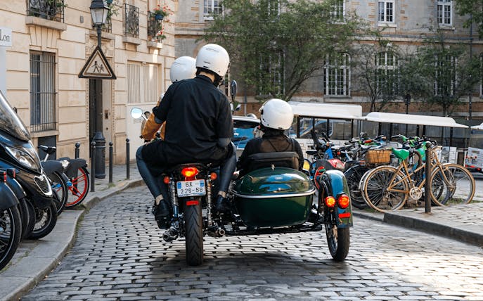 Sidecar motorcycle tour on cobblestone street in Paris.