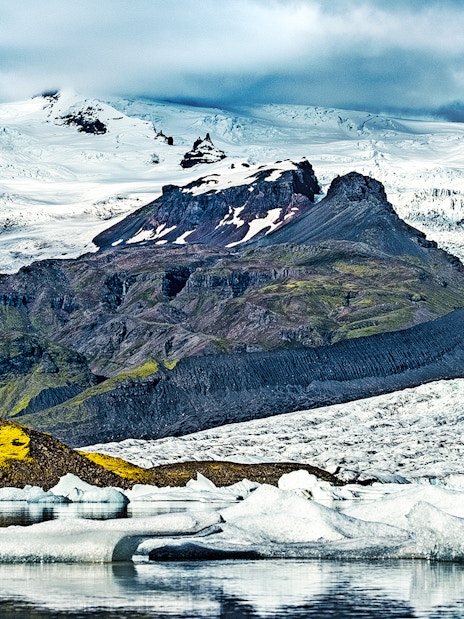 Fjallsarlon Glacier Lagoon with icebergs and snow-covered mountains in Iceland.