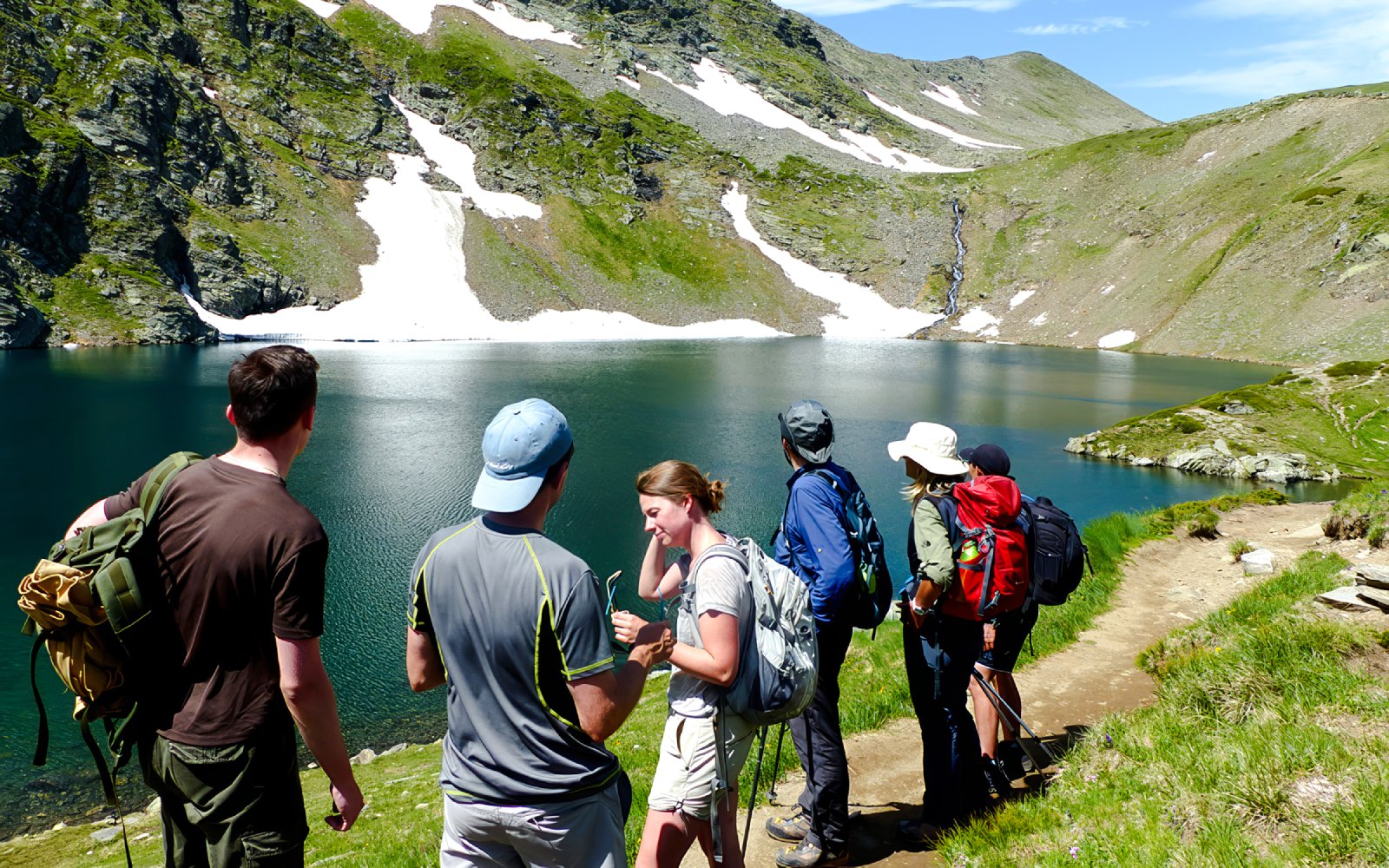 Hikers enjoying the view of a lake and mountains during The Seven Rila Lakes tour from Sofia.