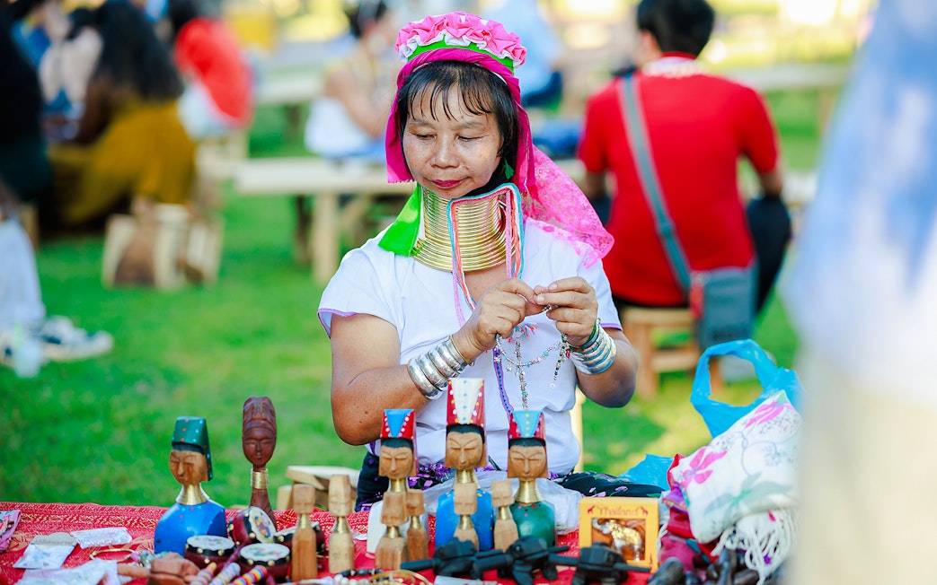 Woman crafting jewelry at Chiang Mai market during Sky Lanterns Festival.