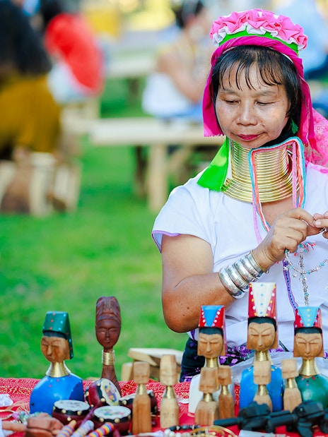 Woman crafting jewelry at Chiang Mai market during Sky Lanterns Festival.