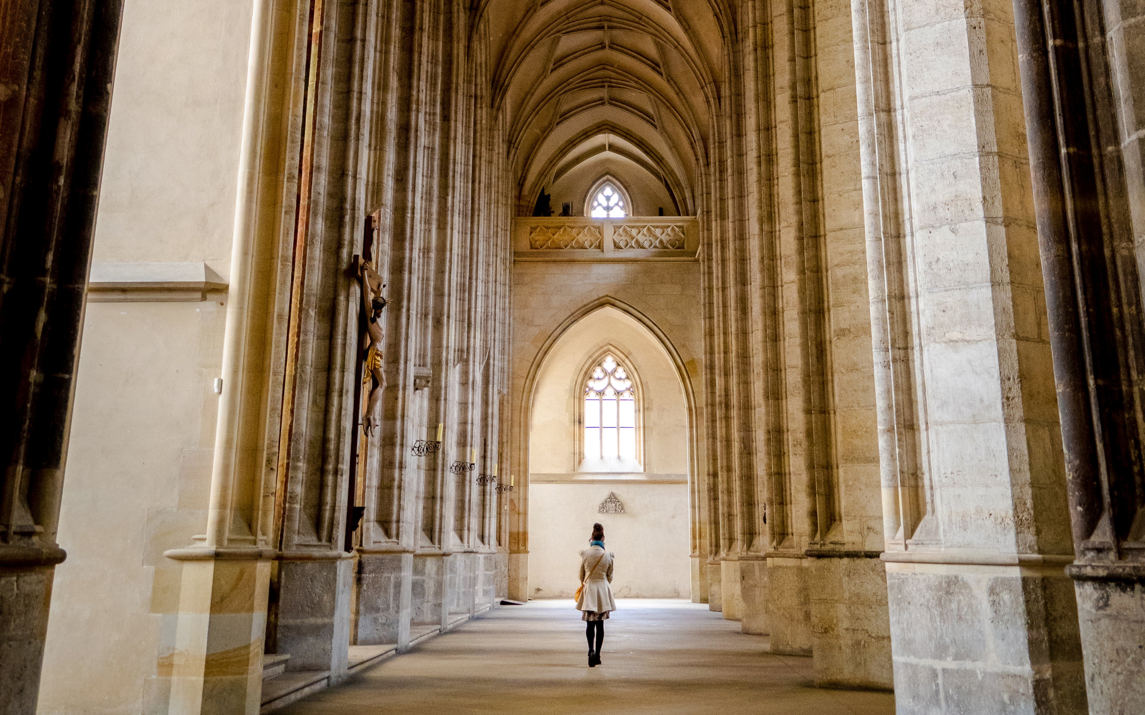 Interior view of St. Barbara's Cathedral in Kutná Hora with vaulted ceilings and a person walking.