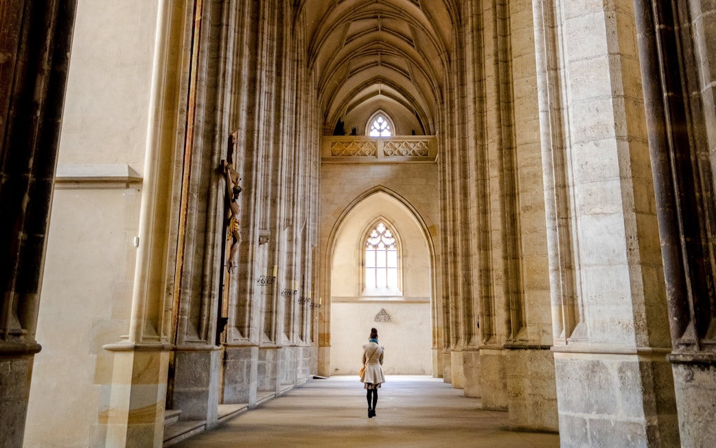 Interior view of St. Barbara's Cathedral in Kutná Hora with vaulted ceilings and a person walking.