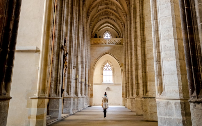 Interior view of St. Barbara's Cathedral in Kutná Hora with vaulted ceilings and a person walking.
