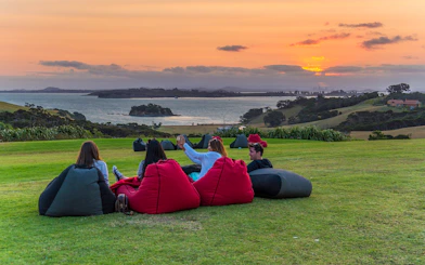 Friends relaxing on bean bags at Cable Bay Vineyard, enjoying wine with a sunset view.