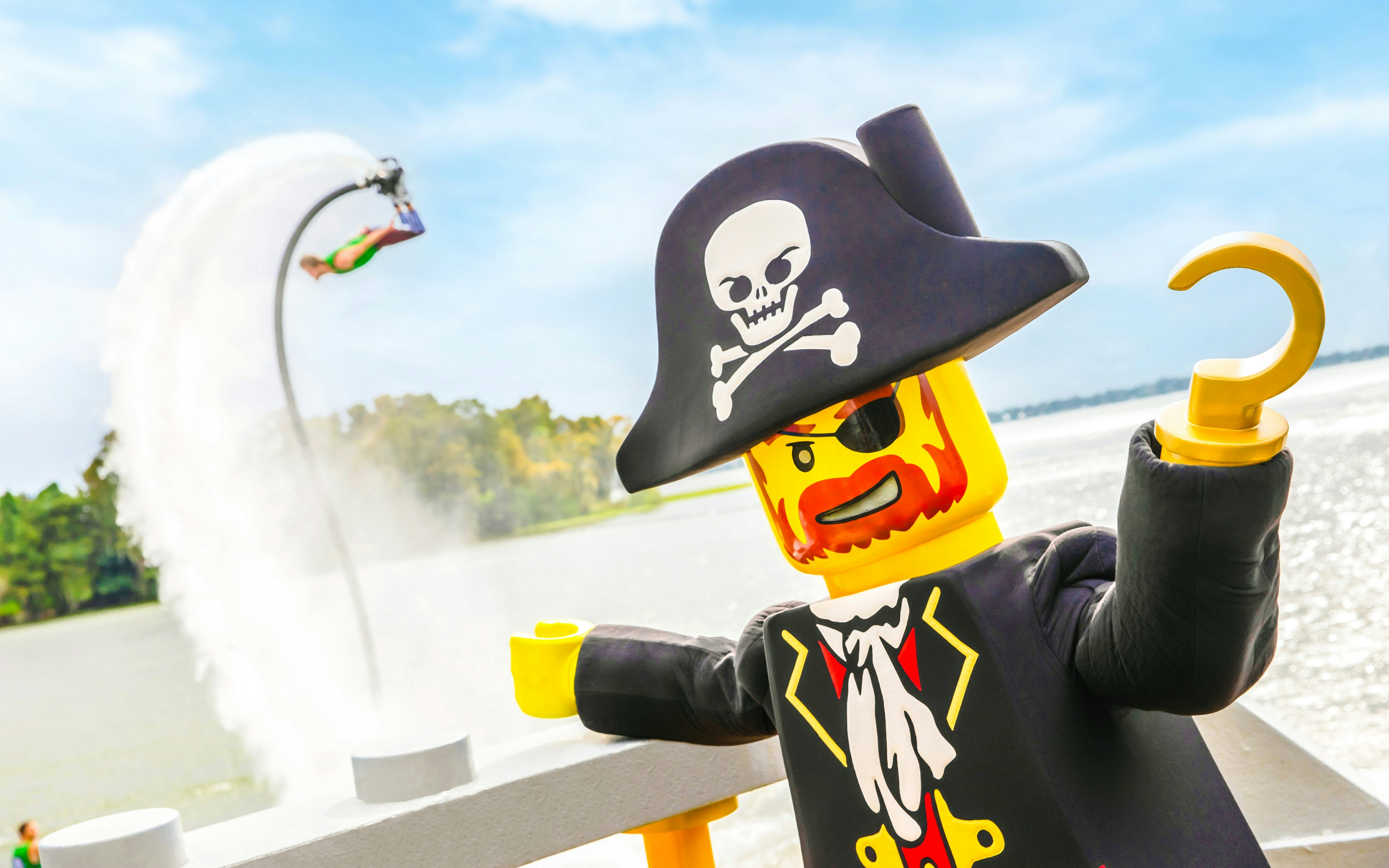 Pirate-themed LEGO figure with hook hand at Pirates’ Cove, LEGOLAND, with water jetpack in background.