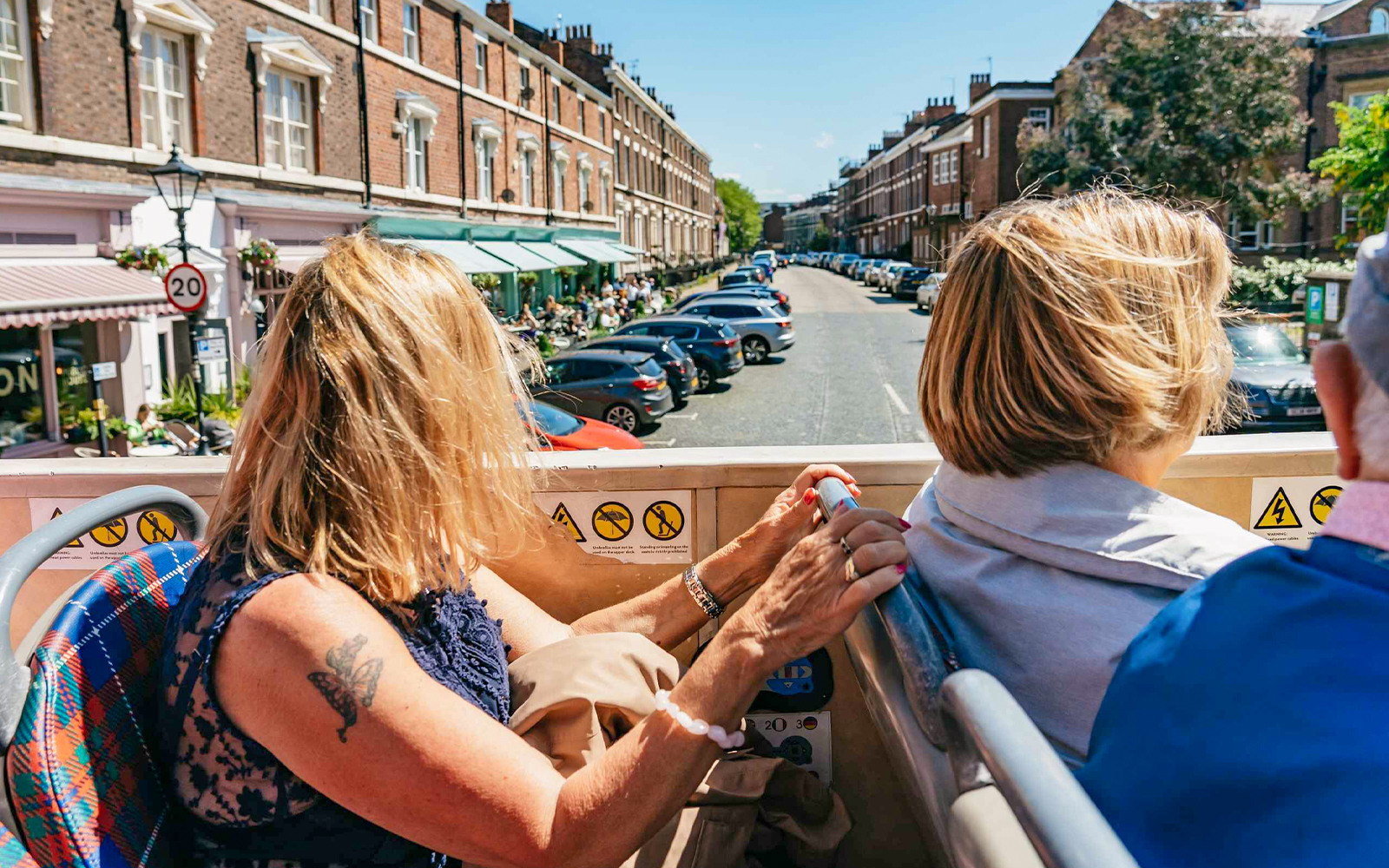 Woman enjoying a hop-on hop-off bus tour in Liverpool, viewing city streets.