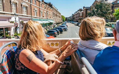 Woman enjoying a hop-on hop-off bus tour in Liverpool, viewing city streets.