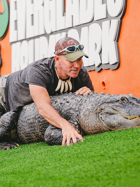 Man interacting with an alligator at Everglades Holiday Park during an airboat tour.