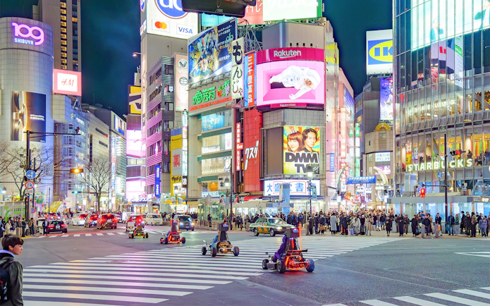 Go-karting at night in Shibuya, Tokyo, with illuminated cityscape and bustling streets.