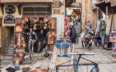 Fes Medina street scene with copper shop and people on a donkey during Chouara Tannery tour.