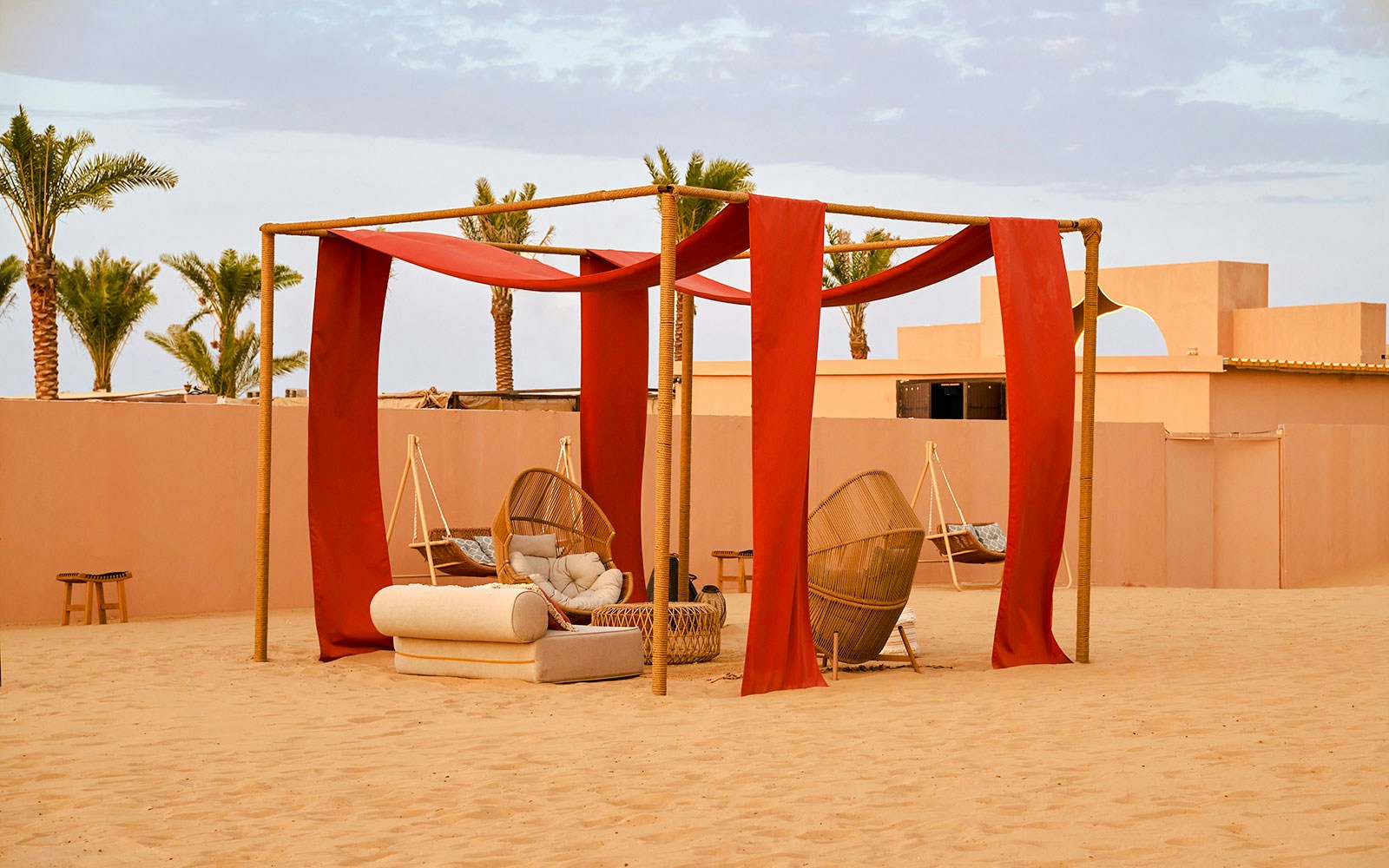 Lounge area with wicker chairs and red drapes at Noble Camp Desert Safari.