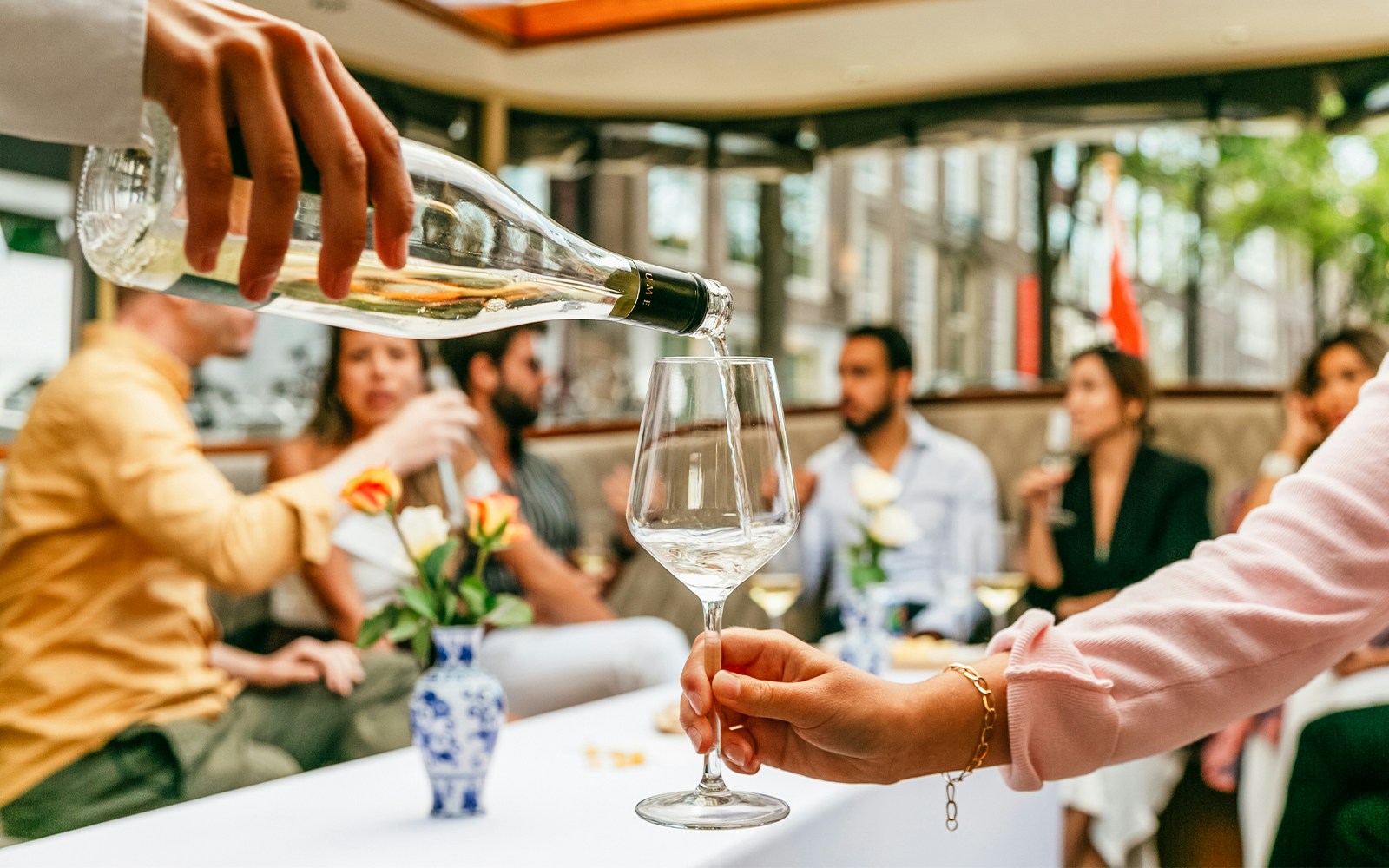 Guests enjoying cheese and wine on a classic boat cruise in Amsterdam canals.