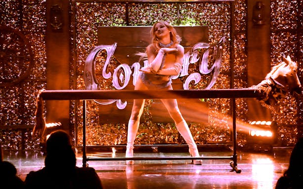 Performer on stage at Kick'n Topless Revue, Vegas, with "Country" sign in background.
